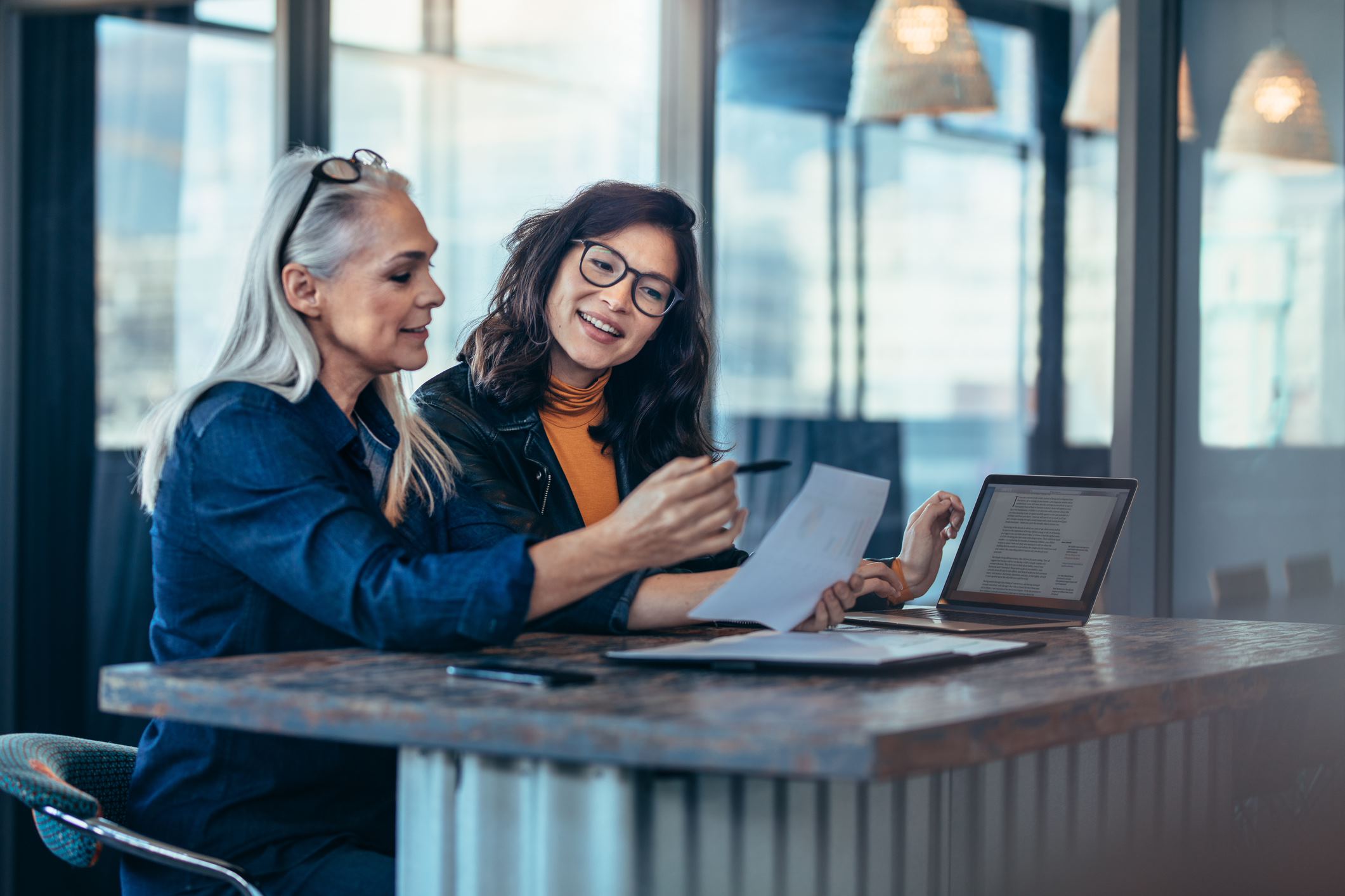 two women reading a document together in an office